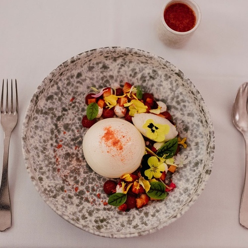 un plato de comida junto a un tenedor y una cuchara
