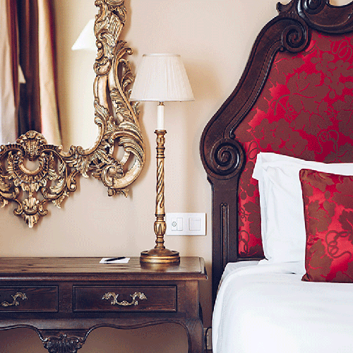 una cama con una almohada roja y una lámpara junto a un espejo