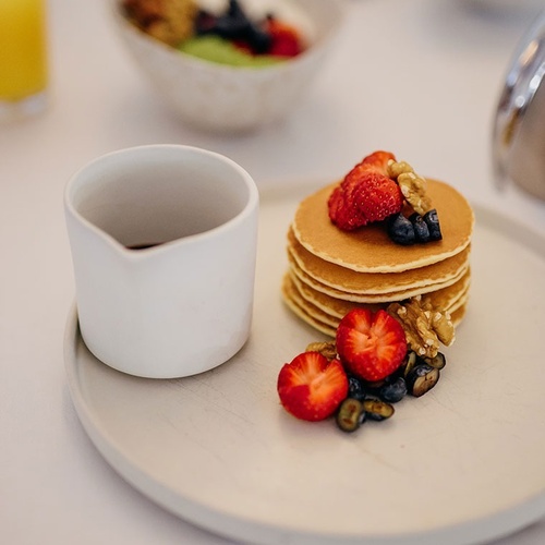 una pila de panqueques con fresas , arándanos y nueces