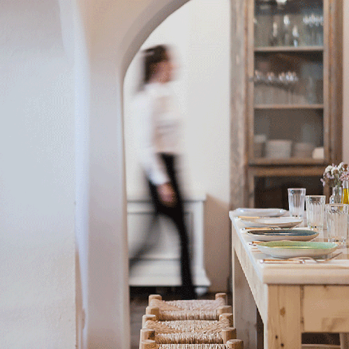 una mesa con platos y vasos y una mujer en el fondo