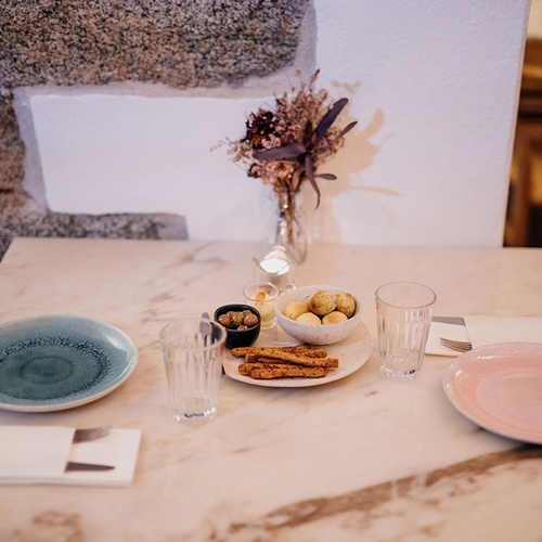 una mesa con platos y vasos y un jarrón de flores