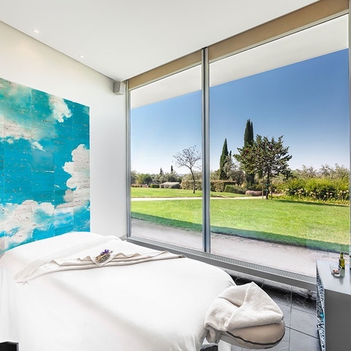 una habitación con una cama y una pintura de nubes en la pared