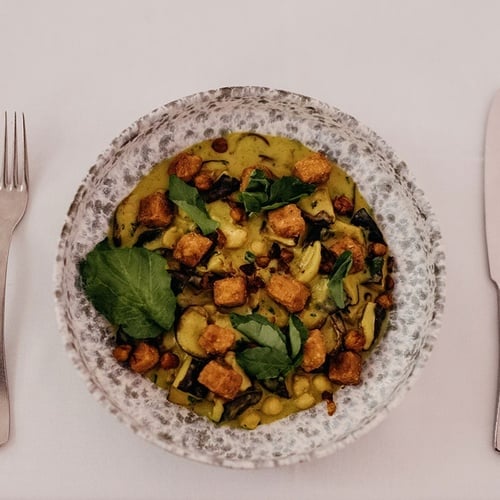 un plato de comida junto a un tenedor y un cuchillo