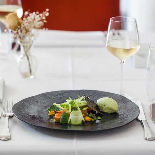 un plato de comida está sobre una mesa junto a un vaso de vino
