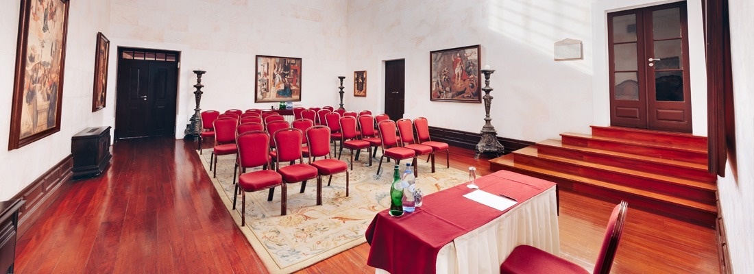 uma sala com muitas cadeiras vermelhas e uma mesa