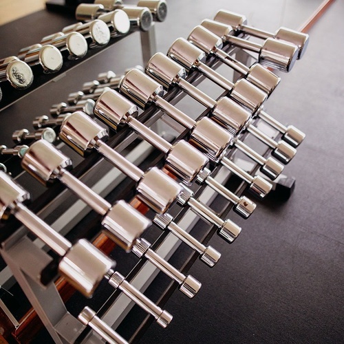 un rack de mancuernas en un gimnasio con la palabra technogym en la parte superior