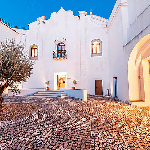 Exterior del Convento do Espinheiro: patio empedrado y fachada blanca.