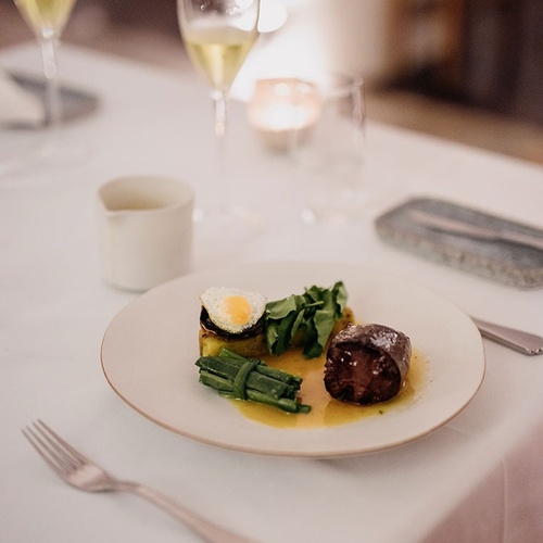 un plato de comida está sobre una mesa con un tenedor y un vaso de vino