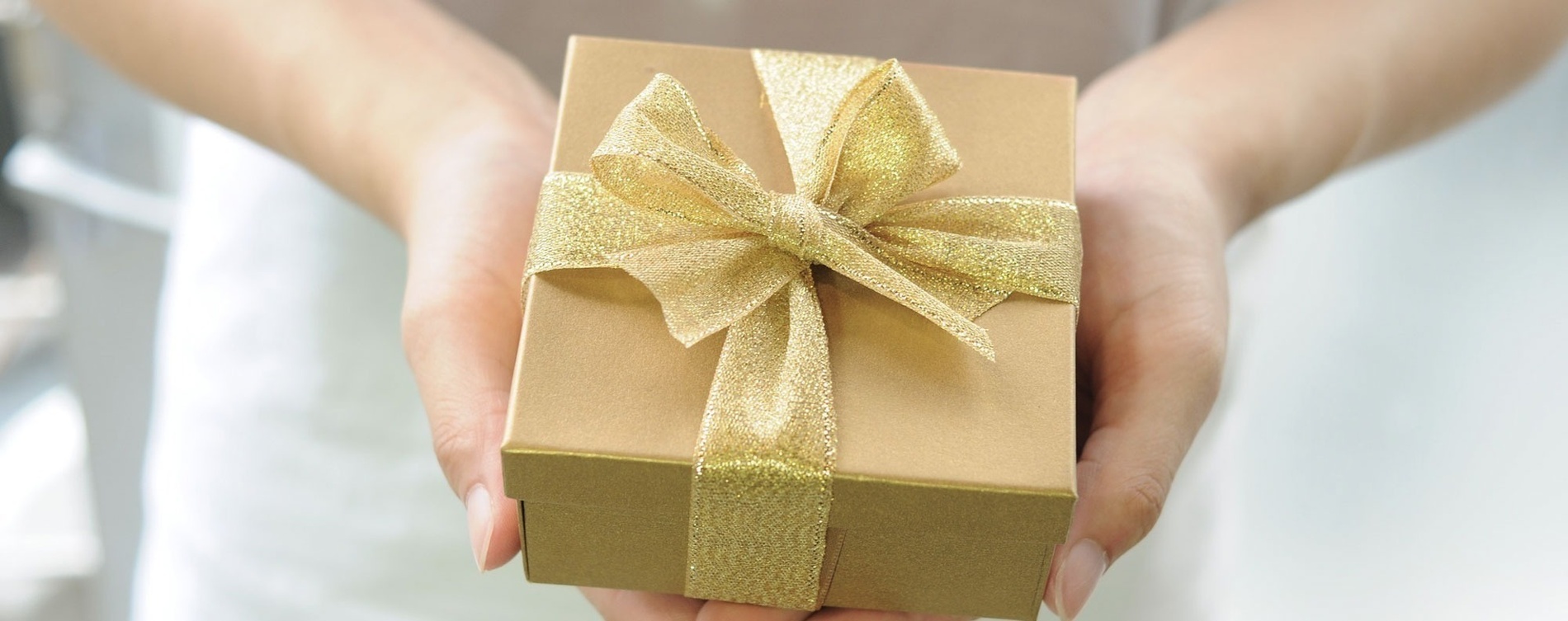 a woman is holding a gift wrapped in brown paper with a tag on it .
