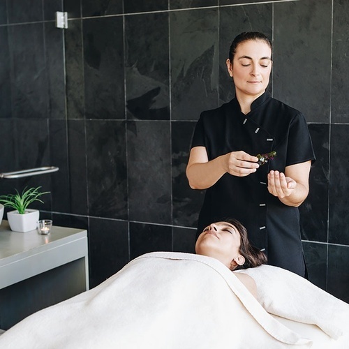 una mujer recibe un masaje en un spa mientras sostiene una botella de aceite