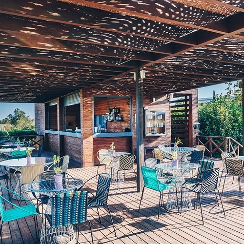 una terraza de madera con mesas y sillas y un bar