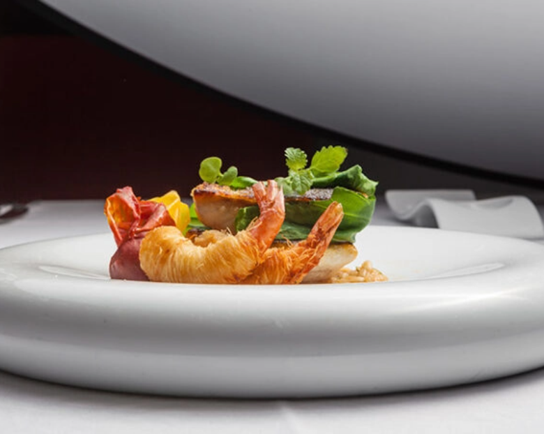 um prato de comida com camarões e bacon em uma mesa