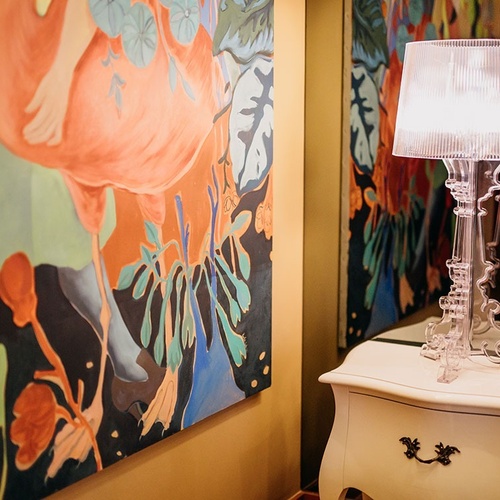 una pintura de flamencos está en la pared junto a un espejo y una lámpara