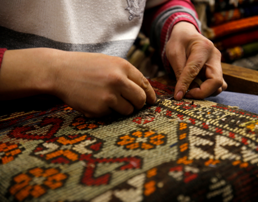 a woman is sitting on a couch holding a piece of embroidered fabric .