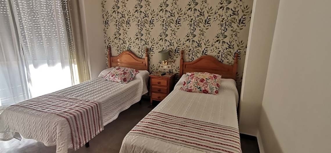 a bedroom with two beds and a floral wallpaper