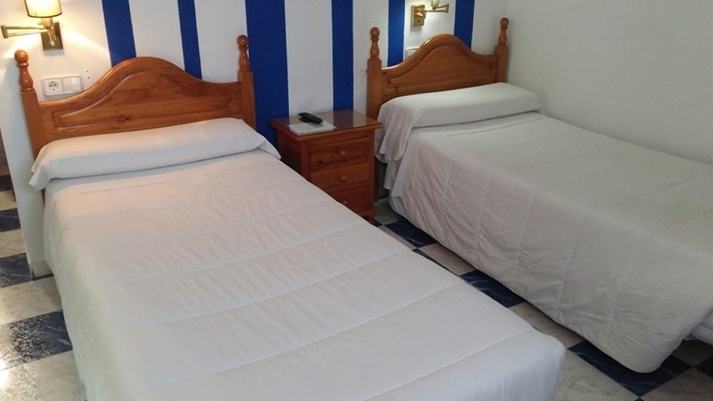 two beds in a bedroom with blue and white stripes on the wall