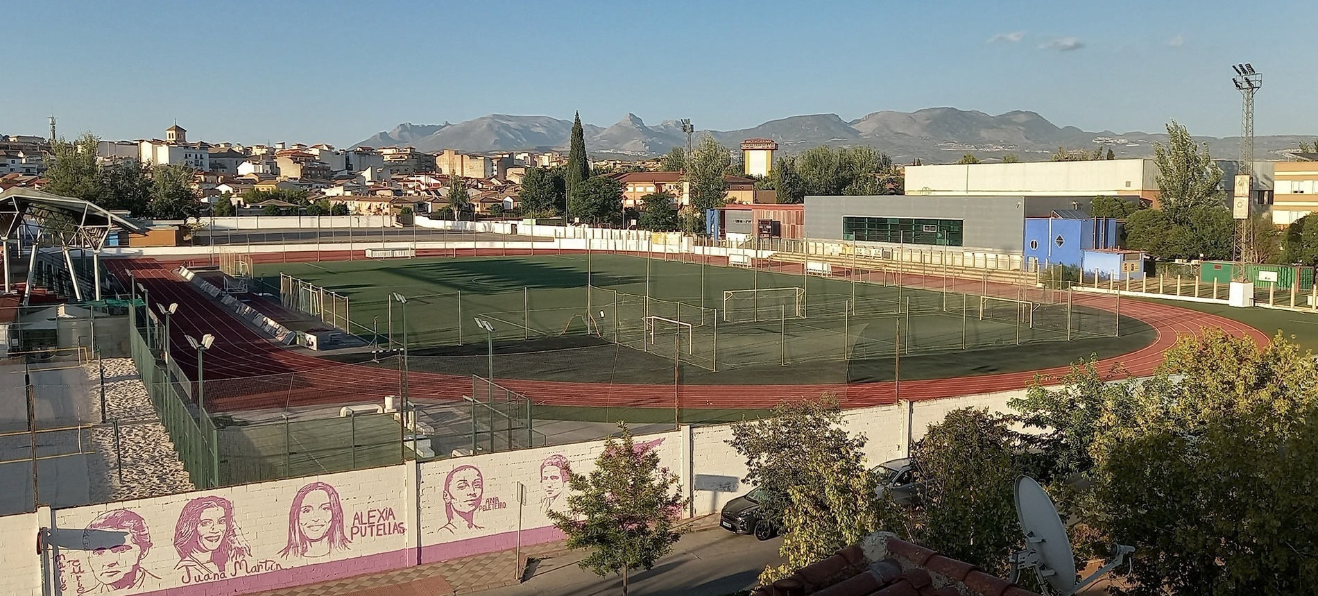 un campo de fútbol con un mural de mujeres y la palabra alfa en la pared