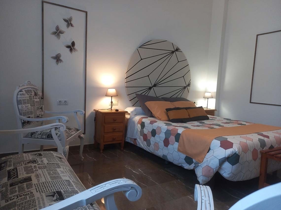 a chair with a newspaper print on it sits next to a bed