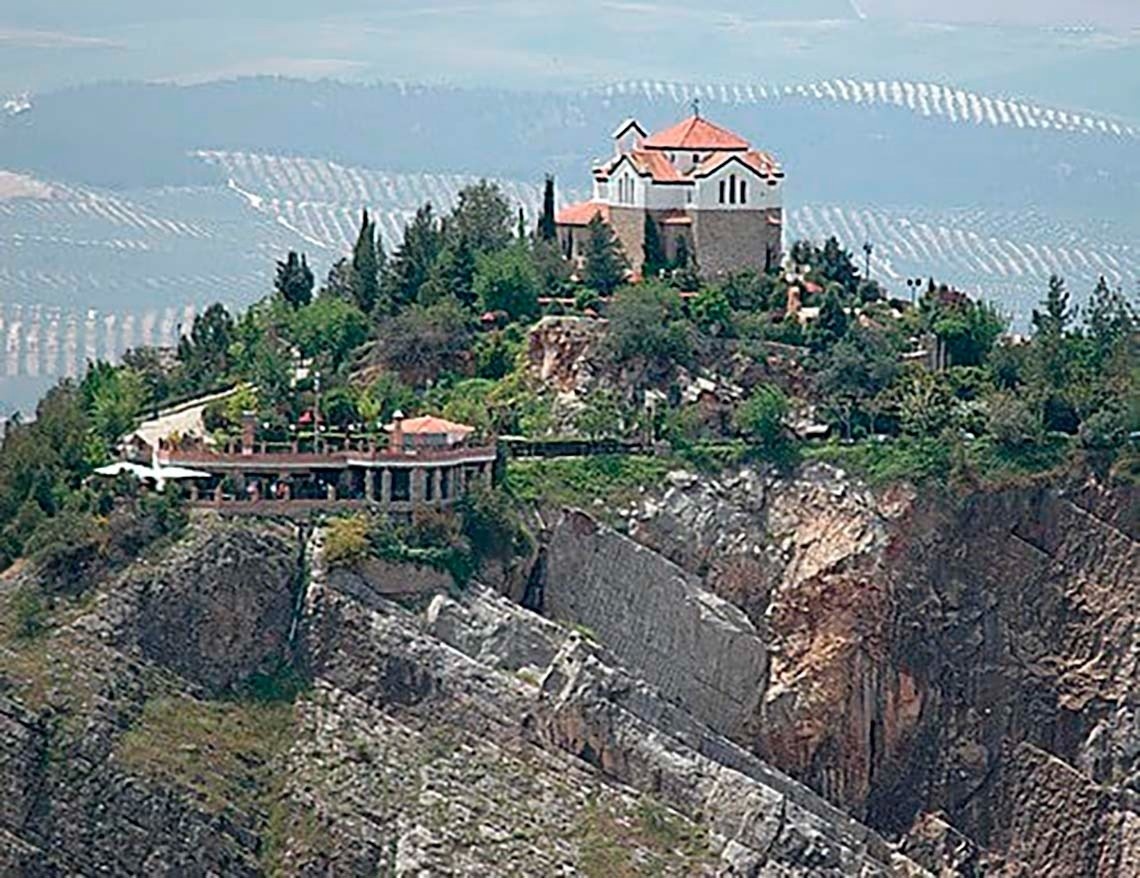 una casa en la cima de una montaña rodeada de árboles y rocas