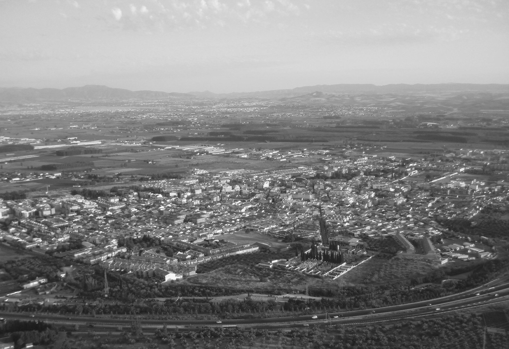 a black and white photo of a city with mountains in the background=s1900