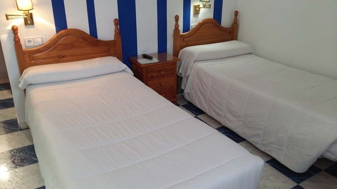 two beds in a bedroom with blue and white stripes on the wall