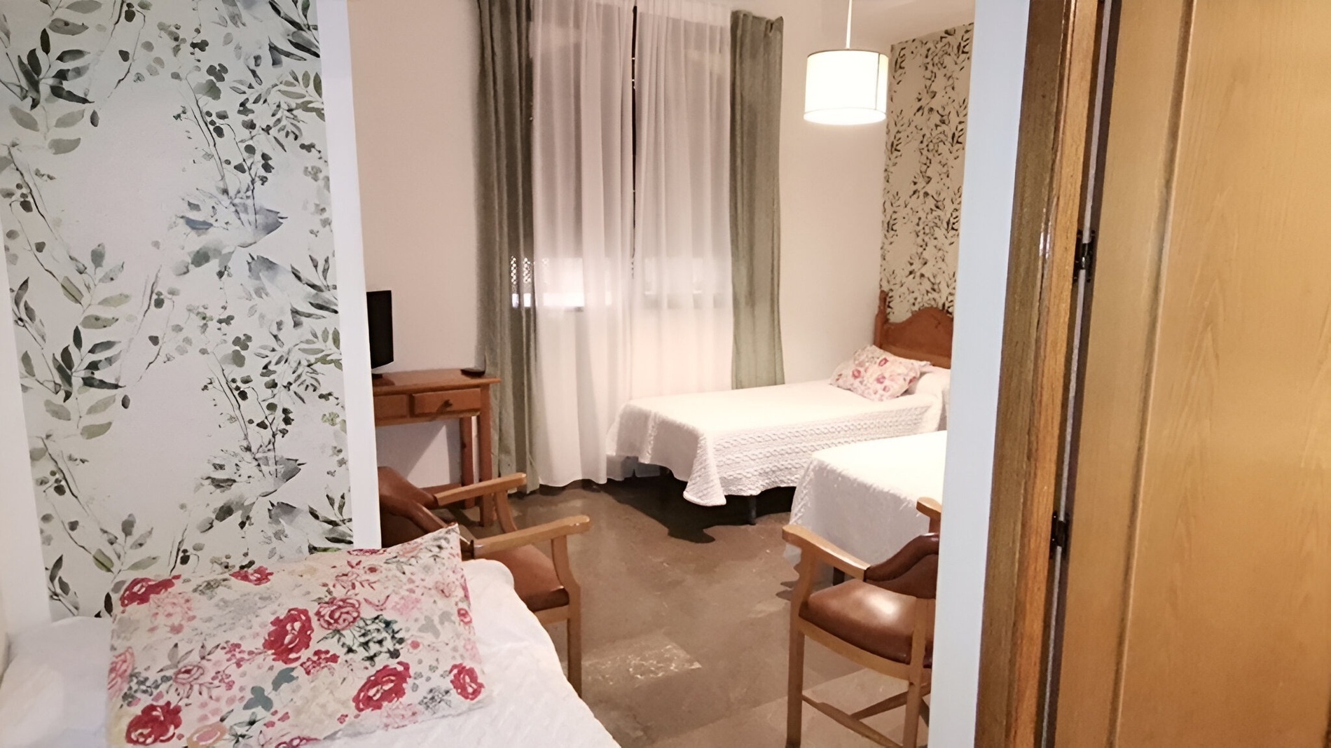 a bedroom with two beds and a floral wallpaper