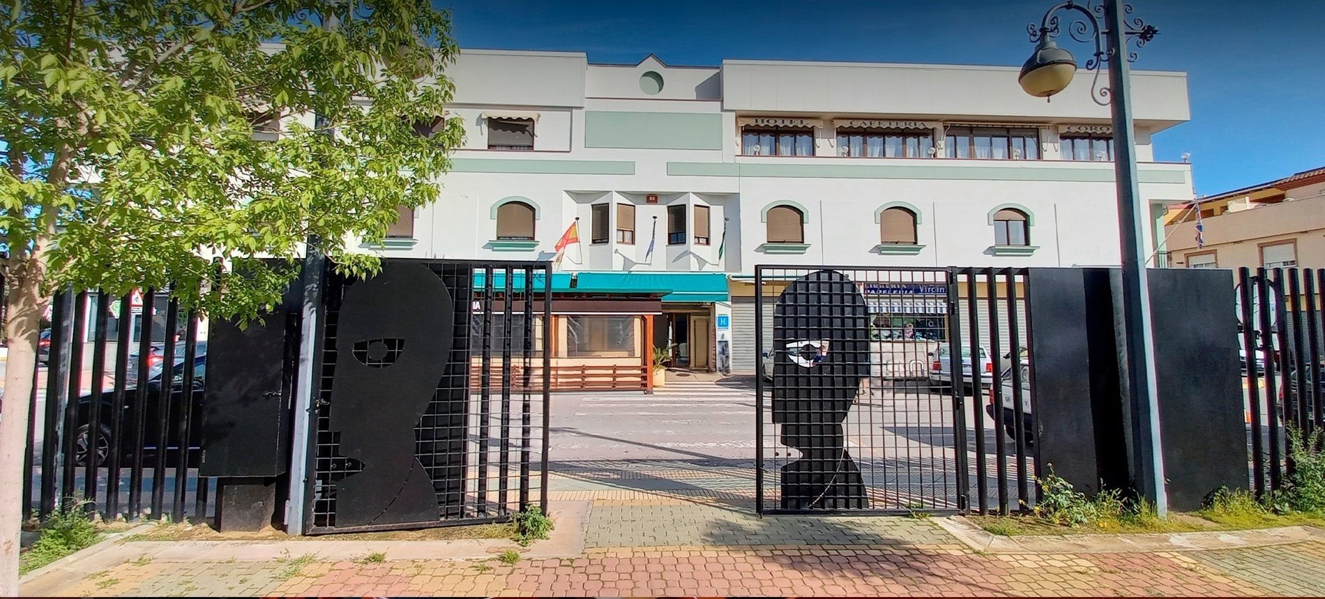 a white building with a green awning is behind a black fence