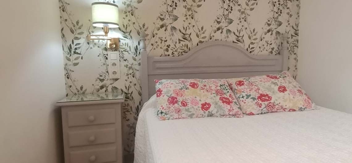 a bedroom with a bed a nightstand and a lamp