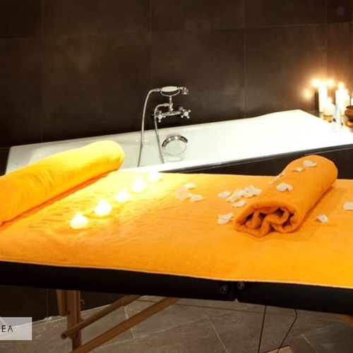 ein massagetisch mit orangefarbenen handtüchern und kerzen in einem badezimmer