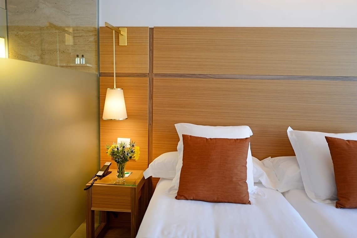 a hotel room with a bed and a nightstand with a vase of flowers on it