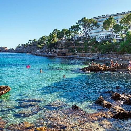 Menschen schwimmen in einem klaren Ozean mit einem Hotel im Hintergrund