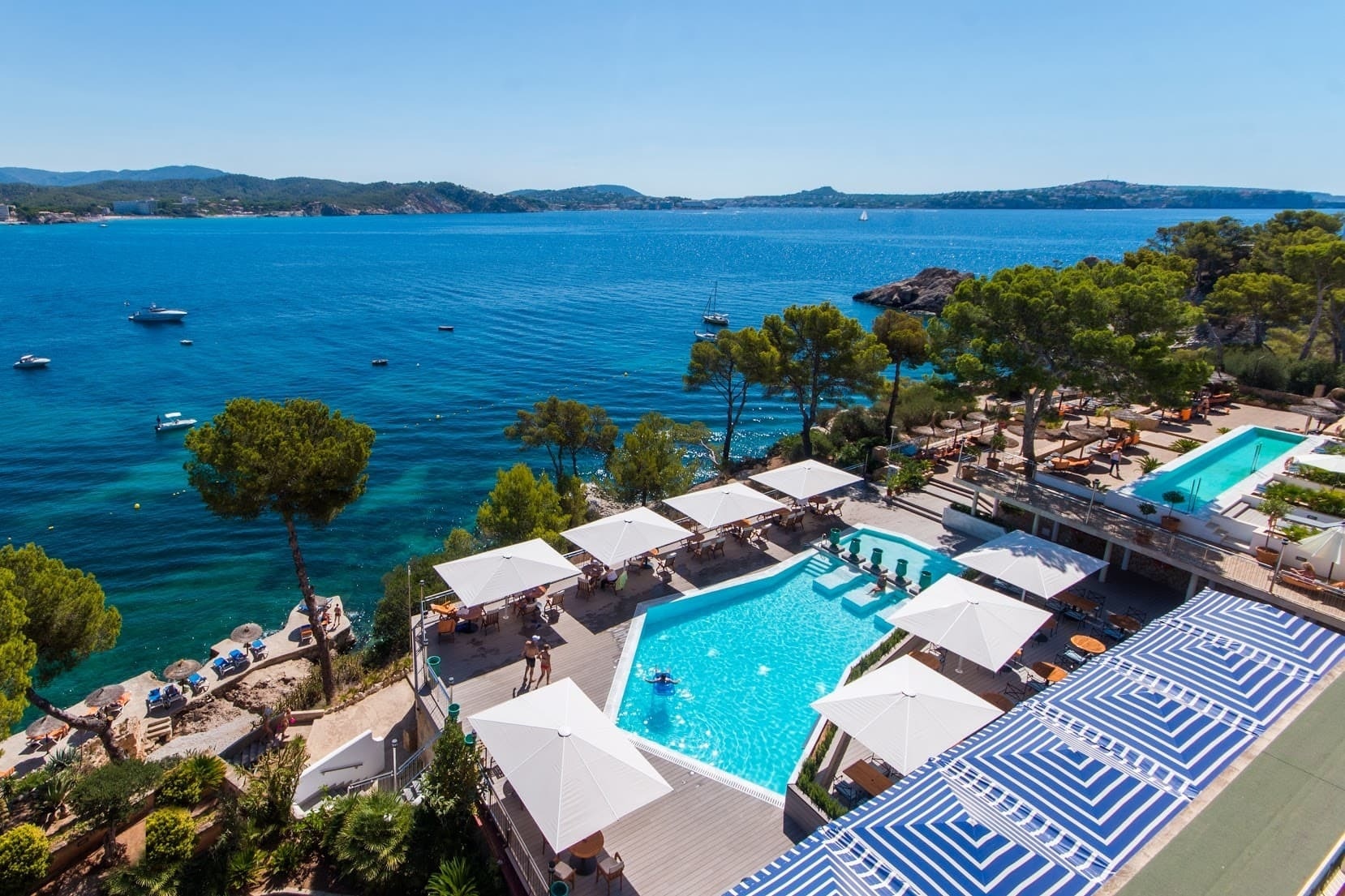 ein großer Pool mit vielen Sonnenschirmen umgeben von einem großen Ozean