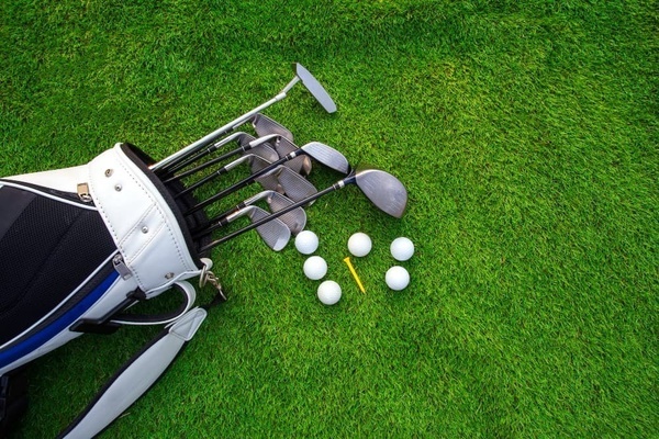 eine Tasche voller Golfschläger und Golfbälle auf einem grünen Rasen