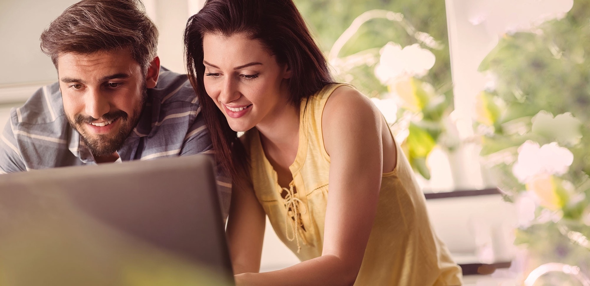 a man and a woman are looking at a laptop together