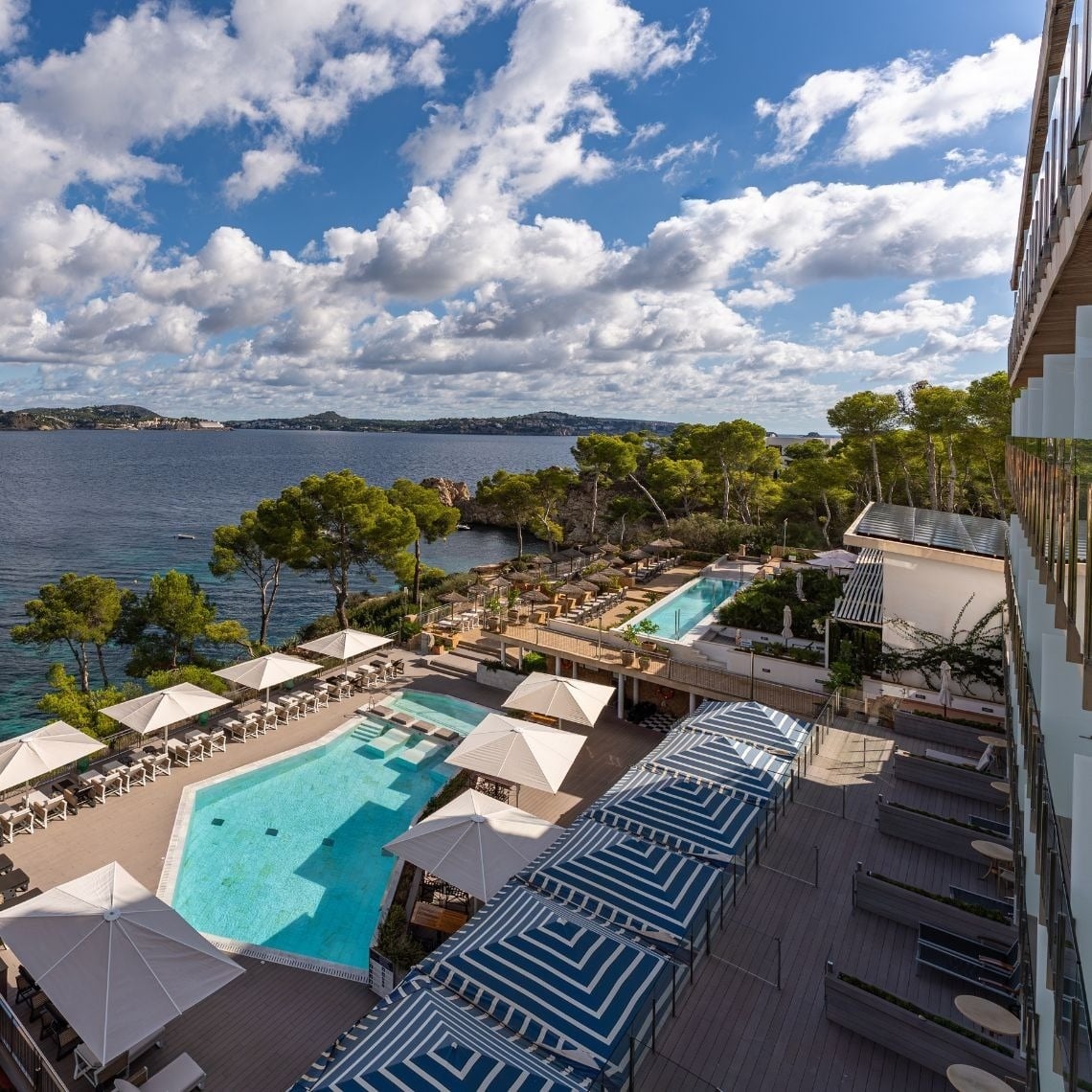 una piscina rodeada de sillas y sombrillas con vista al océano