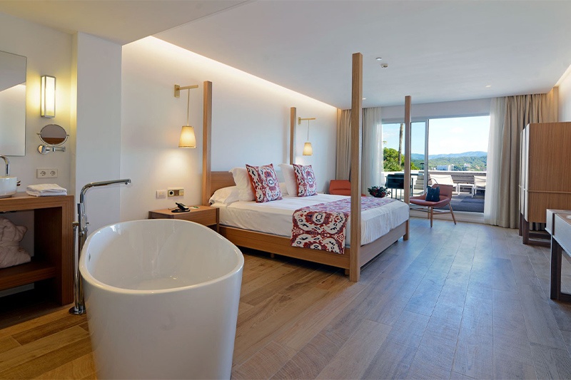 Habitación espaciosa en Hotel Gran Fornells con bañera exenta y cama baldaquino.