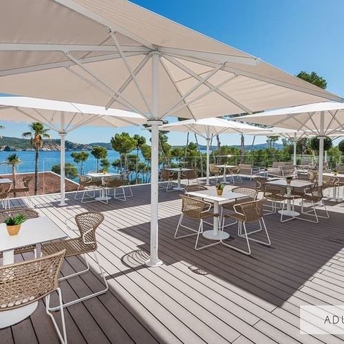 ein Deck mit Tischen und Stühlen und Regenschirmen mit der Aufschrift 