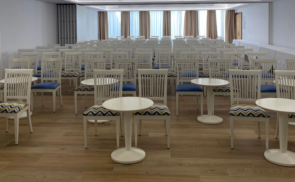 rows of white chairs and tables in a room