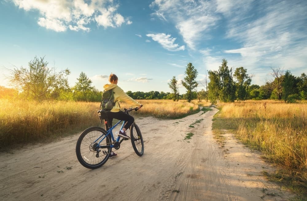 eine Frau fährt mit einem Fahrrad auf einem Feldweg