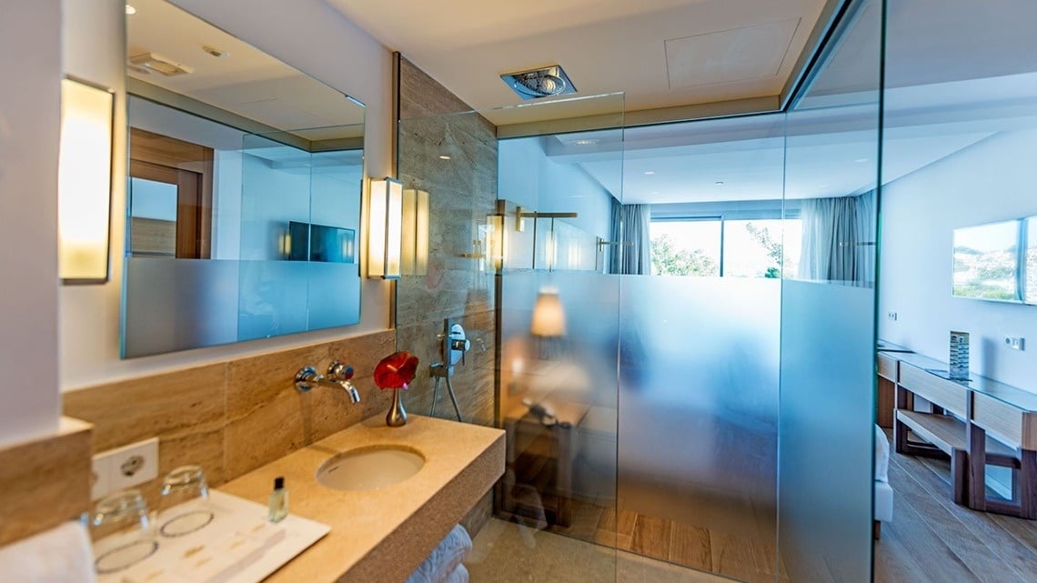 un baño con puerta de vidrio y lavabo