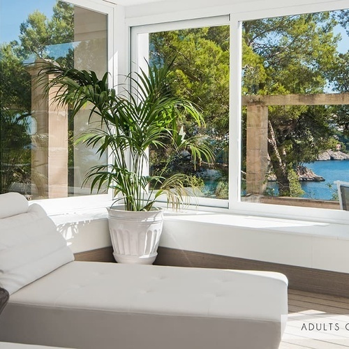 ein Wohnzimmer mit einem Stuhl und einer Pflanze neben einem Fenster