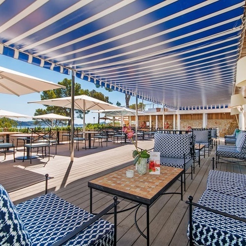 eine Terrasse mit blau-weiß gestreiften Sonnenschirmen und Möbeln