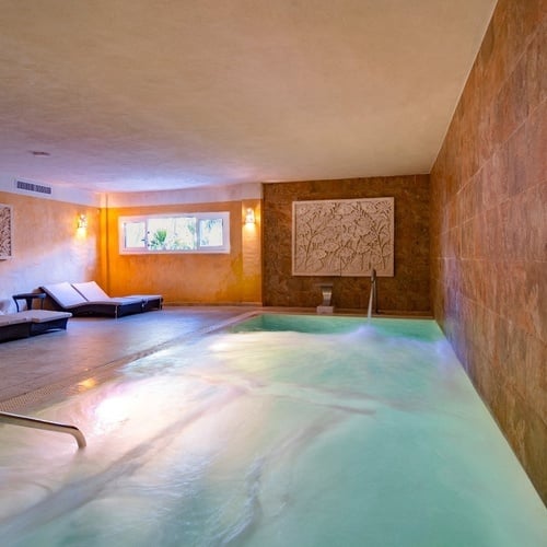 a swimming pool in a room with chairs and a picture on the wall