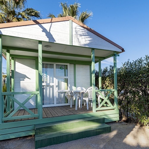 una cabaña de madera blanca y verde con una mesa y sillas en el porche