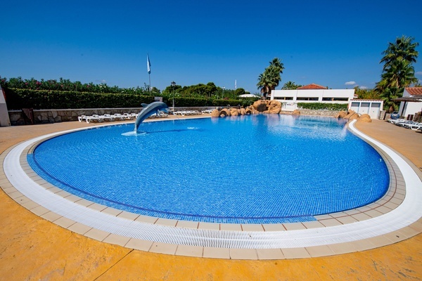 un hombre y una mujer nadan bajo una cascada en una piscina