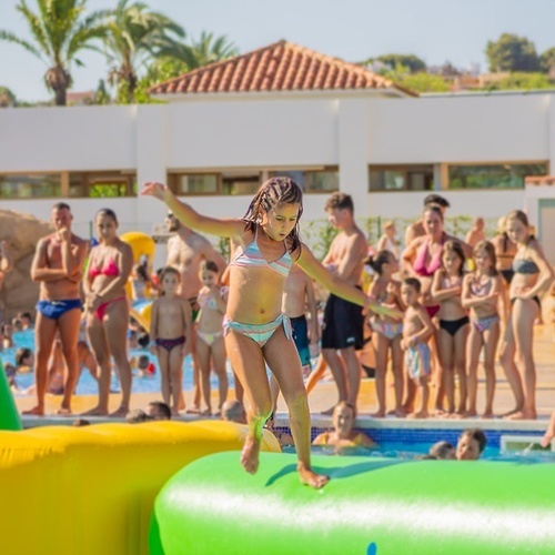 una niña salta de un colchón inflable en una piscina