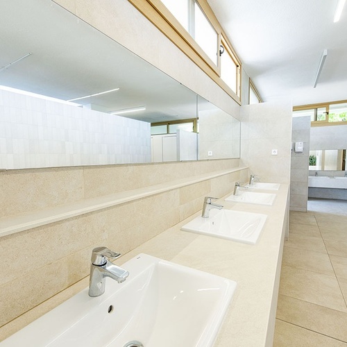 un baño con lavabos y espejos y un banco de madera