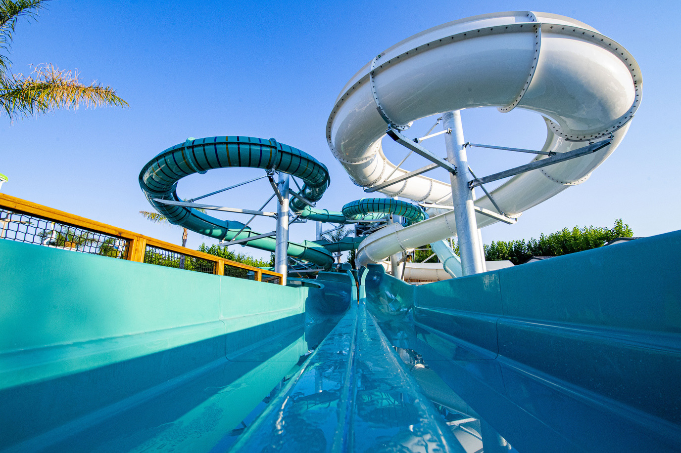 Toboganes de agua de Creixell camping & family resort, tubos blancos y verdes bajo el cielo azul.