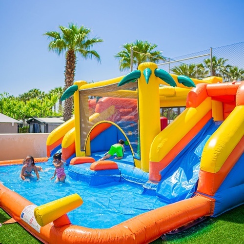 dos niños juegan en una piscina inflable con un tobogán