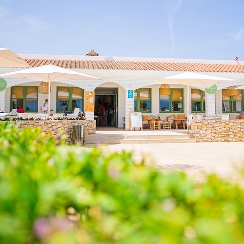 un edificio blanco con una puerta verde y un letrero que dice ' abierto '